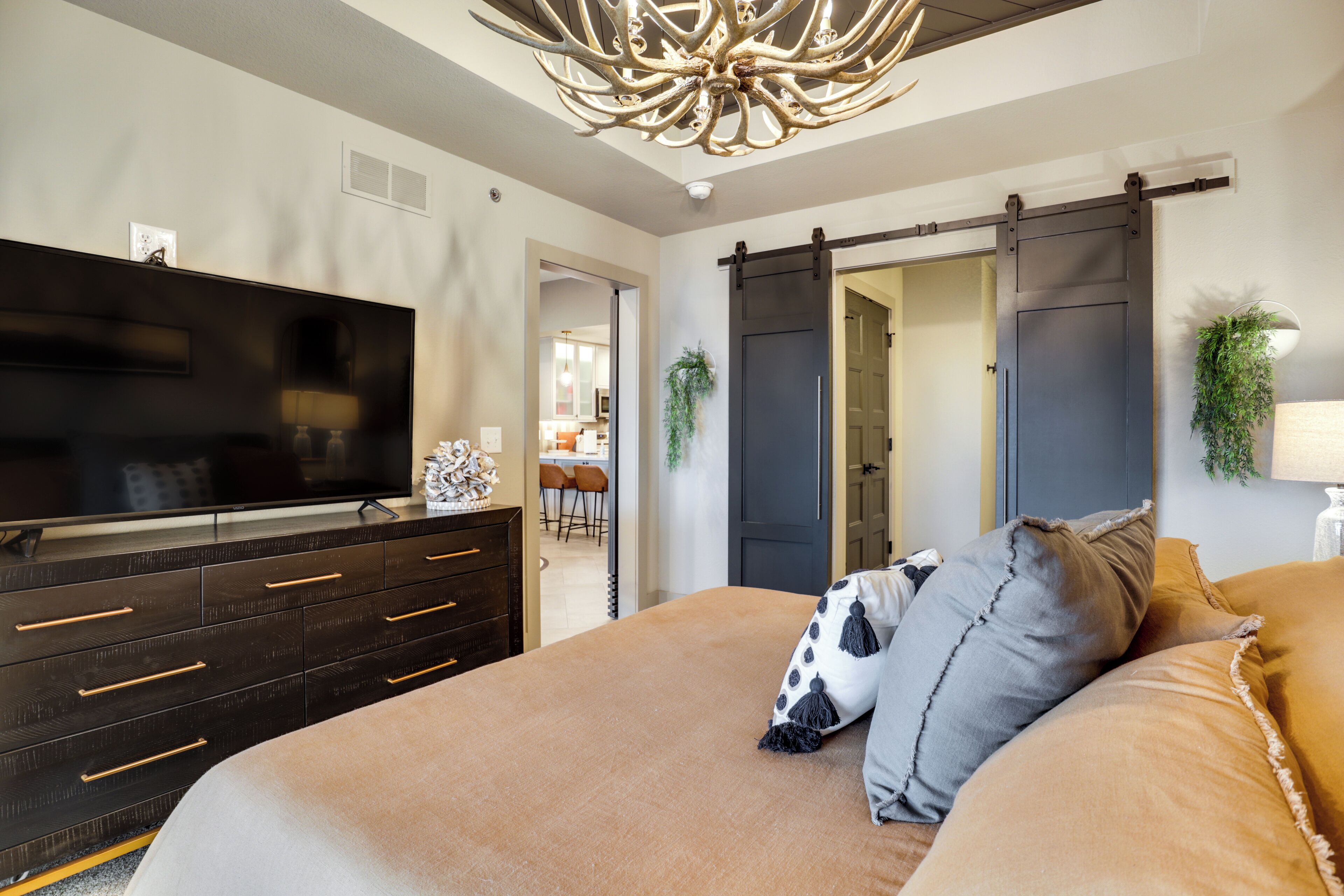 Une chambre avec un grand lit, un téléviseur posé sur une commode et un placard à portes coulissantes de style grange.