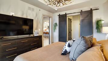 Une chambre avec un grand lit, un téléviseur posé sur une commode et un placard à portes coulissantes de style grange.