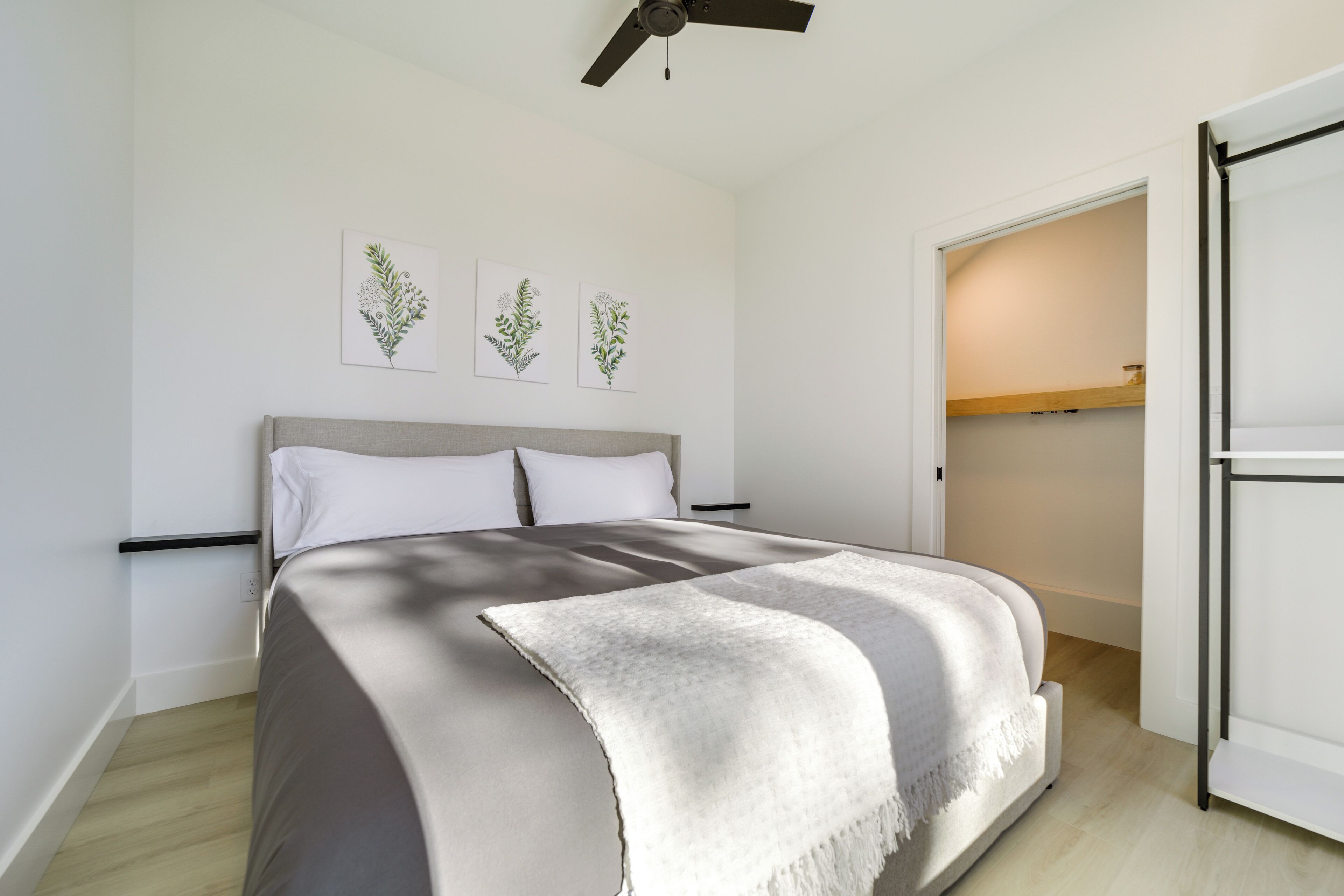 A bedroom with a bed, a ceiling fan, and a door leading to a closet.