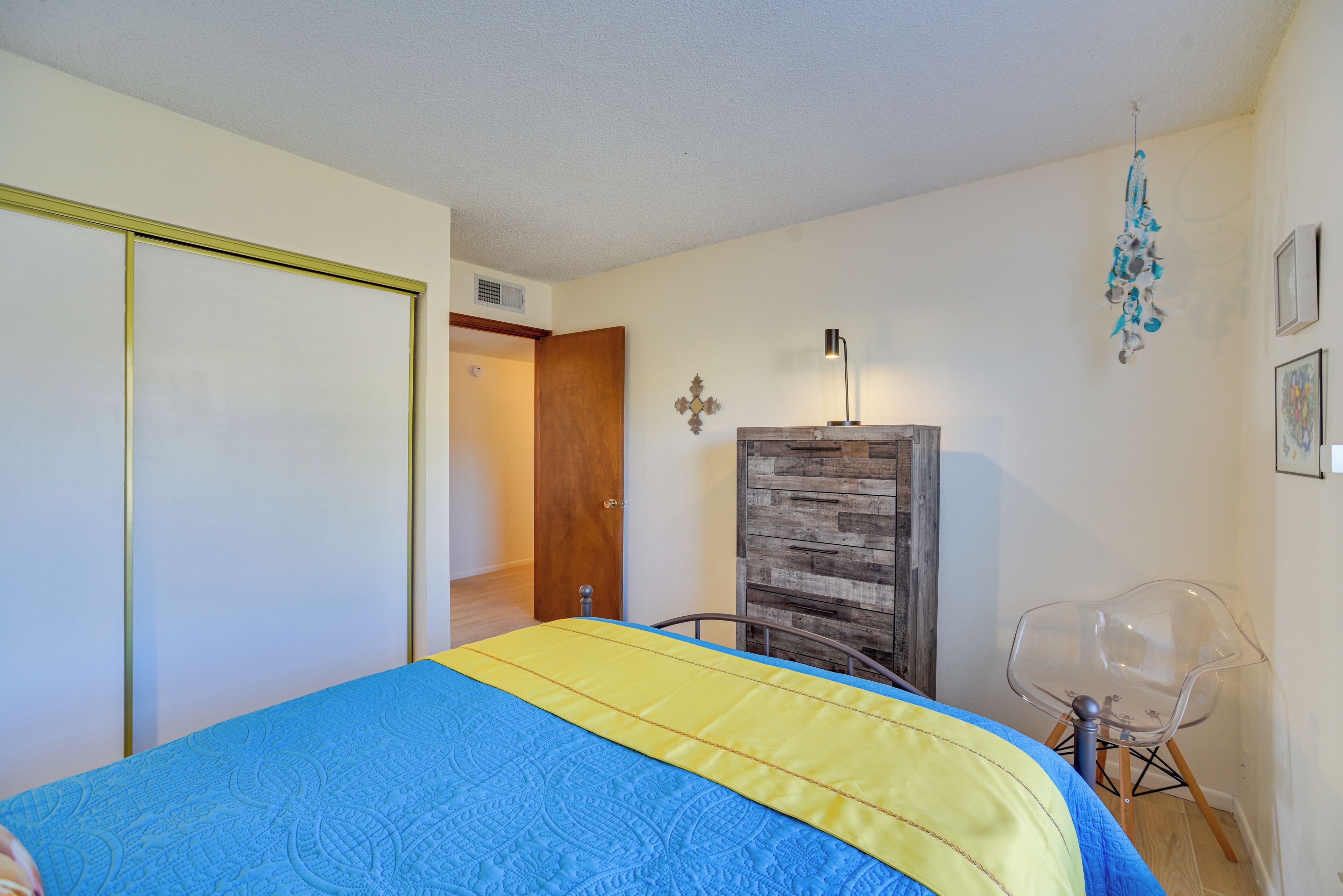Ein Schlafzimmer mit einem Bett, einem Kleiderschrank, einem Sessel und einer Wandlampe.