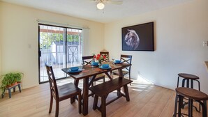 A dining area with a table set for four, wooden chairs, a ceiling fan, and a large window with a view of the outside. - Adobe Home in Albuquerque w/ Covered Patio (Albuquerque)