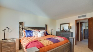 A bedroom with a wooden bed, a nightstand, a dresser, and a mirror. - Adobe Home in Albuquerque w/ Covered Patio (Albuquerque)