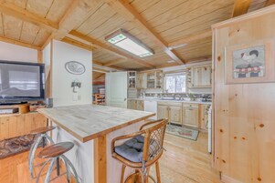 A wooden cabin interior with a kitchen, dining area, and bar.
