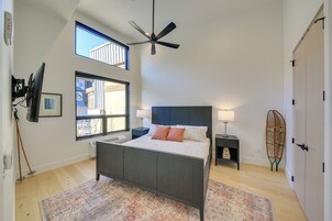Un dormitorio con cama, ventilador de techo, ventana, lámpara de pie y puerta.