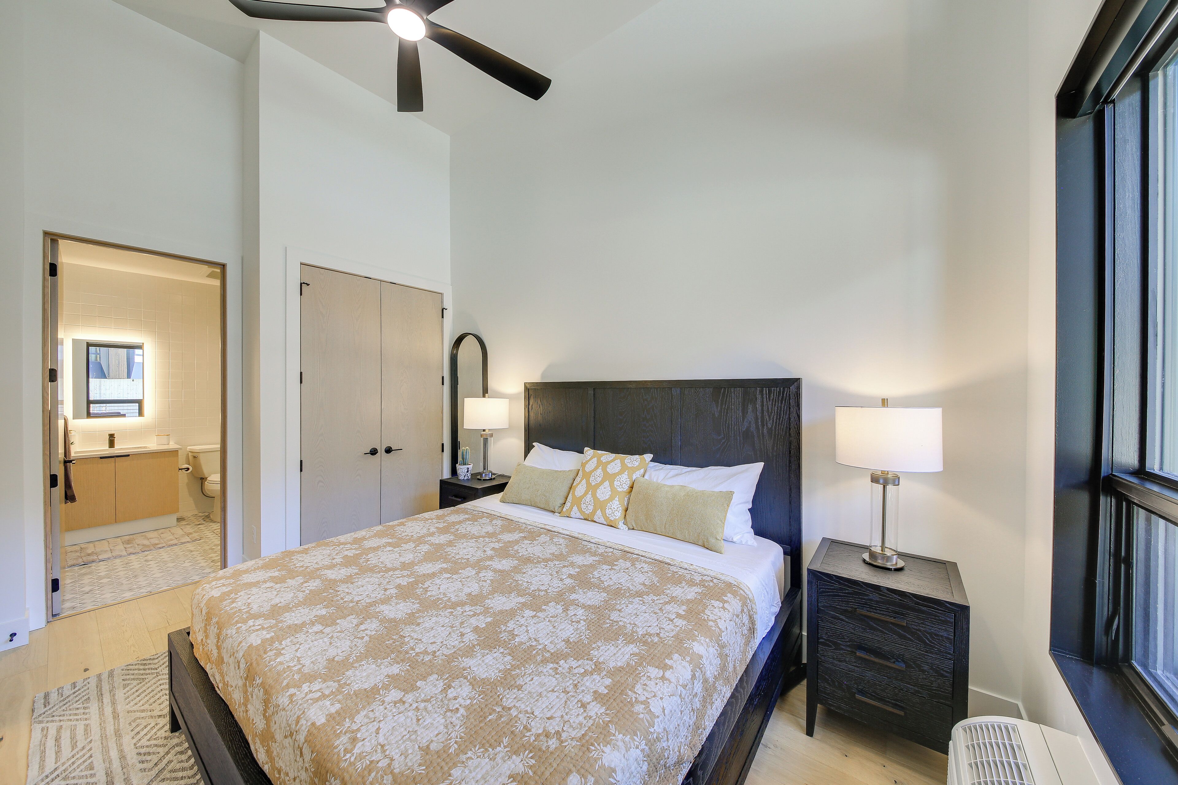 A bedroom with a bed, bedside tables, a ceiling fan, and a window.