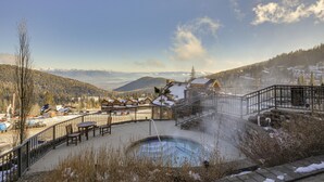A hot spring area with a pool, outdoor seating, and a view of snow-covered mountains and houses. - Luxe Schweitzer Condo w/ Hot Tub: Ski-in/ski-out! (Sandpoint)