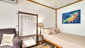 A bedroom with a bed, a chair, a lamp, a wall-mounted rack, and a painting. - Peaceful Norfork Escape: Walk to White River! (Norfork)