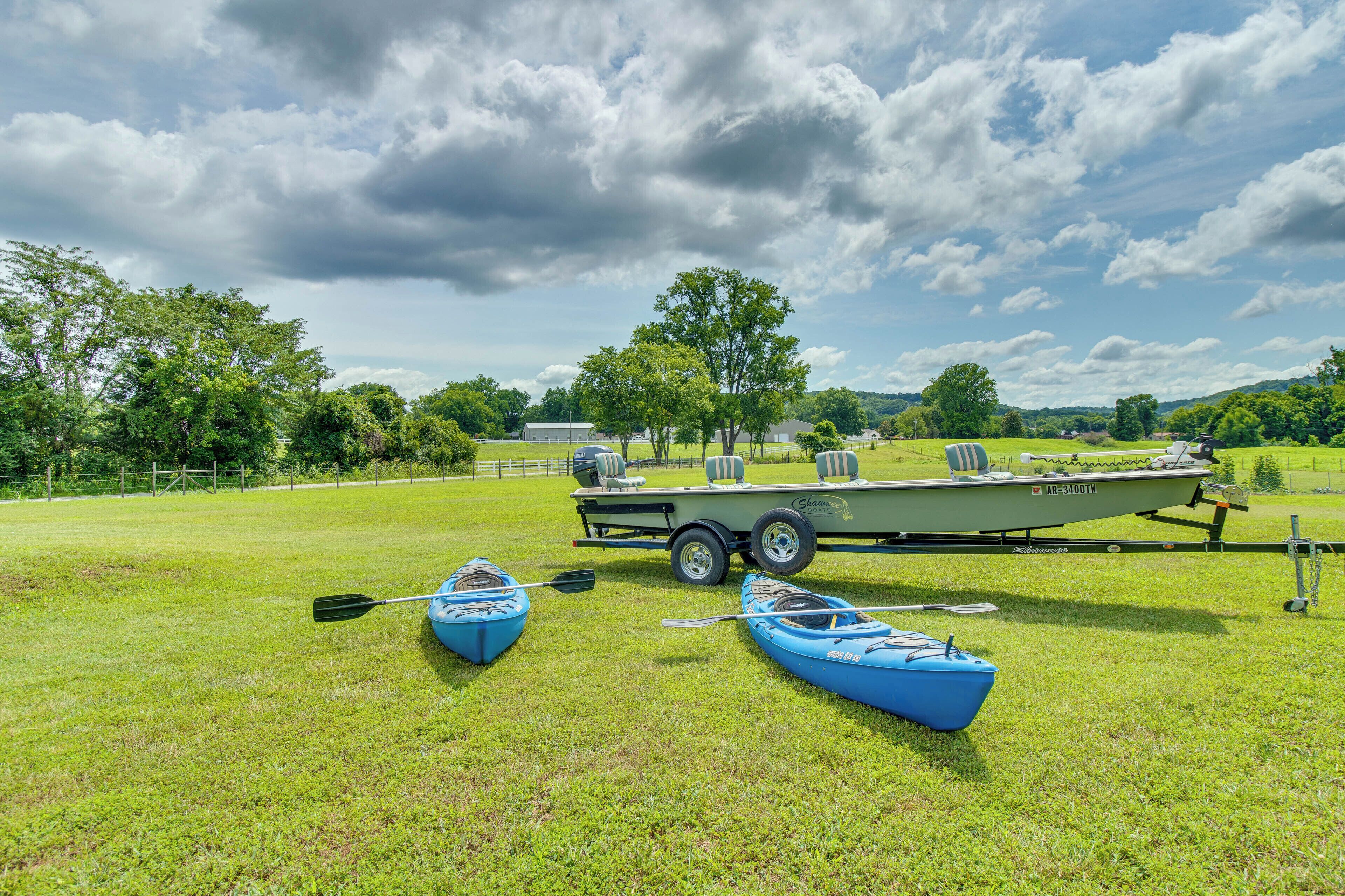 A grassy field with two kayaks and a boat trailer.