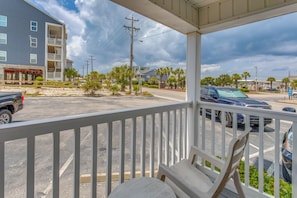 A covered outdoor area with a white railing, a table, and chairs. - Steps to Ocean: High-end North Myrtle Beach Condo (North Myrtle Beach)