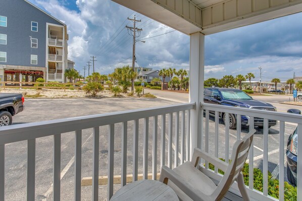 A covered outdoor area with a white railing, a table, and chairs. - Steps to Ocean: High-end North Myrtle Beach Condo (North Myrtle Beach)
