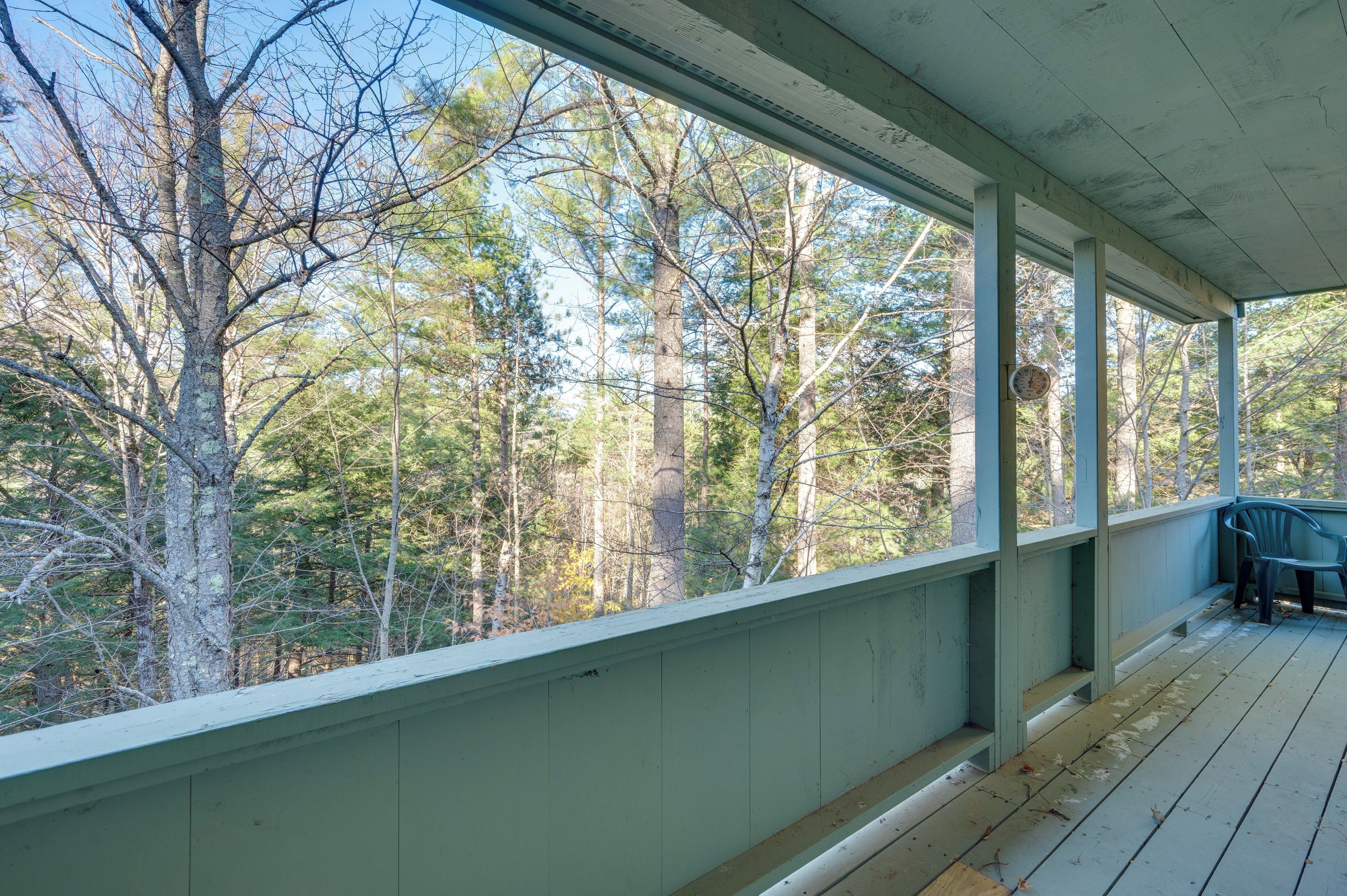A covered porch with a view of a forest.
