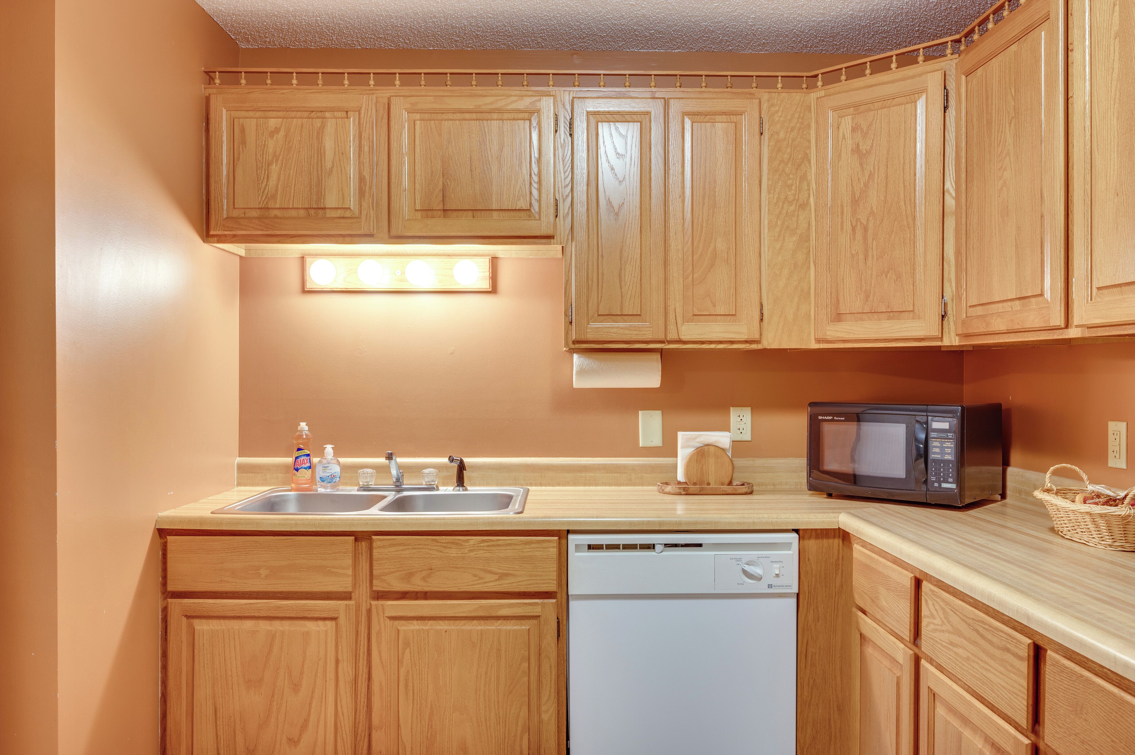 A kitchen with wooden cabinets, a dishwasher, a microwave, and a sink.