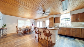 A spacious kitchen with wooden cabinets, a central island, and a dining area with wooden chairs. - North Jackson Vacation Rental w/ Wraparound Deck! (North Jackson)