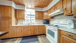 A kitchen with wooden cabinets, a microwave, an oven, and a sink. - North Jackson Vacation Rental w/ Wraparound Deck! (North Jackson)