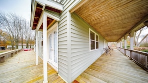 A covered wooden deck with a view of a house and trees. - North Jackson Vacation Rental w/ Wraparound Deck! (North Jackson)