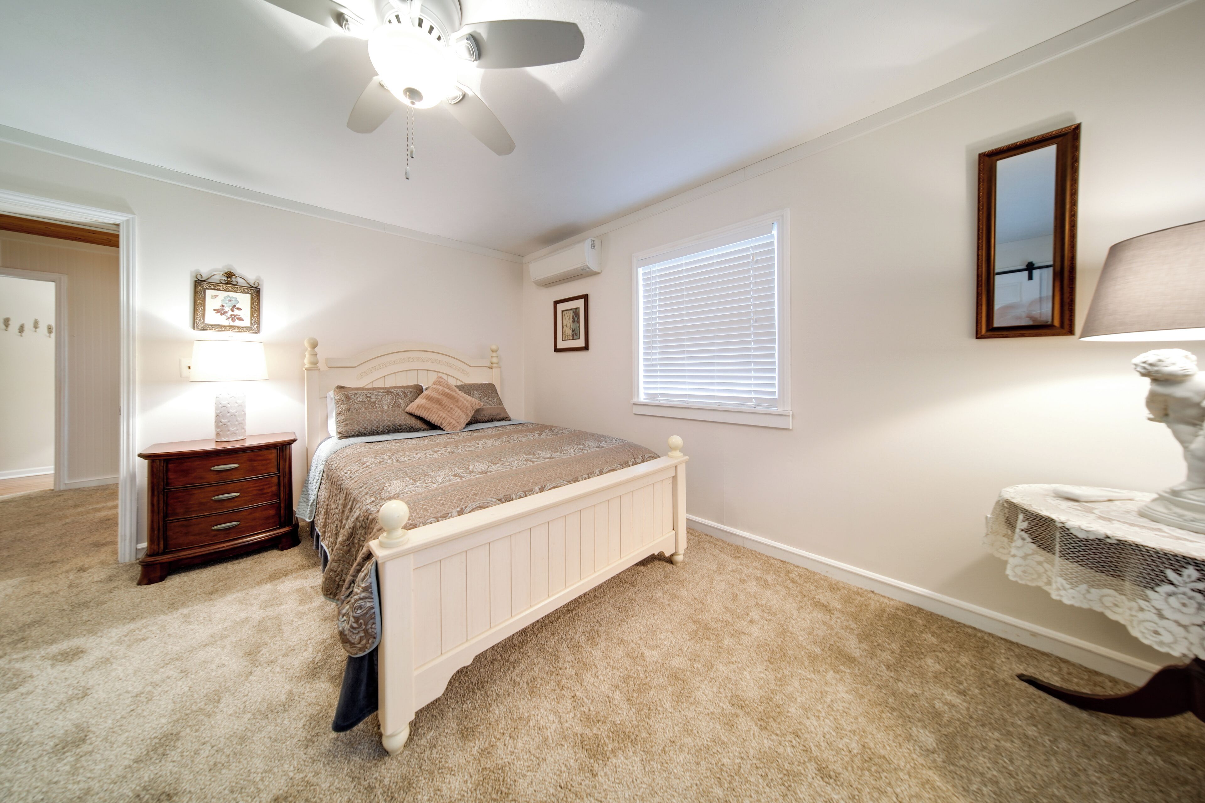 Une chambre à coucher avec un lit, une table de chevet, une lampe et un ventilateur de plafond.