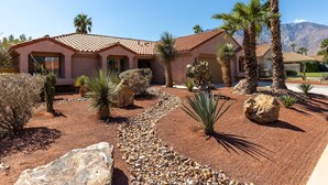 A house with a tiled roof, palm trees, and a rocky garden. - La Buena Vida – Palm Springs Pool & Spa Retreat (Palm Springs)