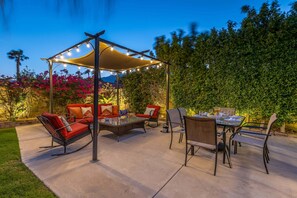 An outdoor patio with a covered seating area, a dining table, and chairs.