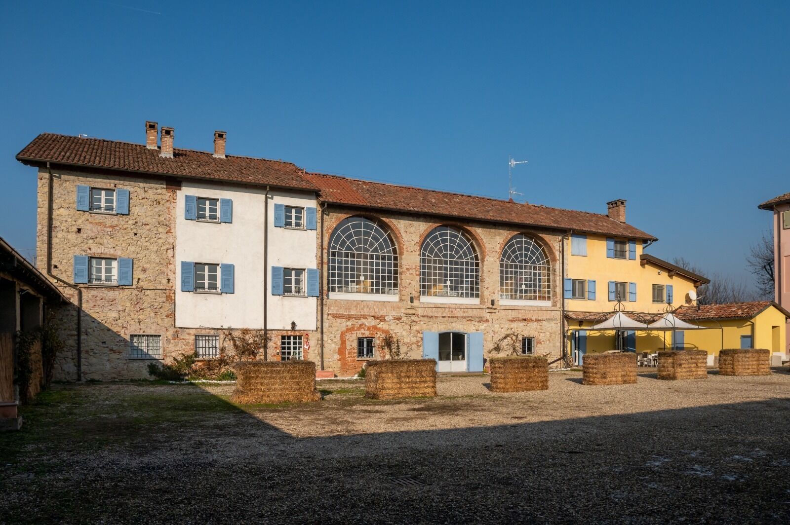 Un edificio histórico con varias ventanas y un patio de grava.