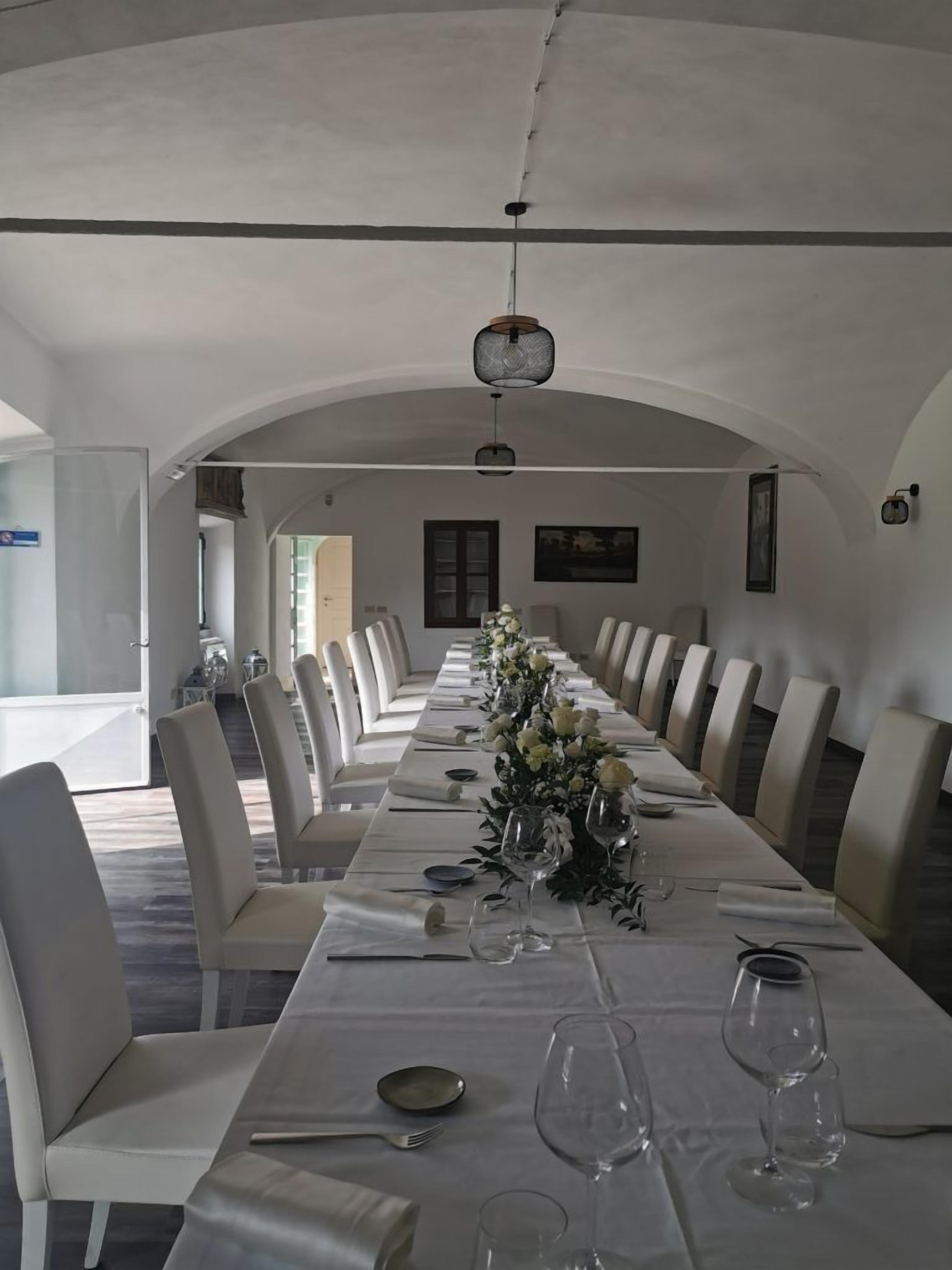 Una larga mesa de comedor con sillas, un centro de mesa floral y copas de vino.