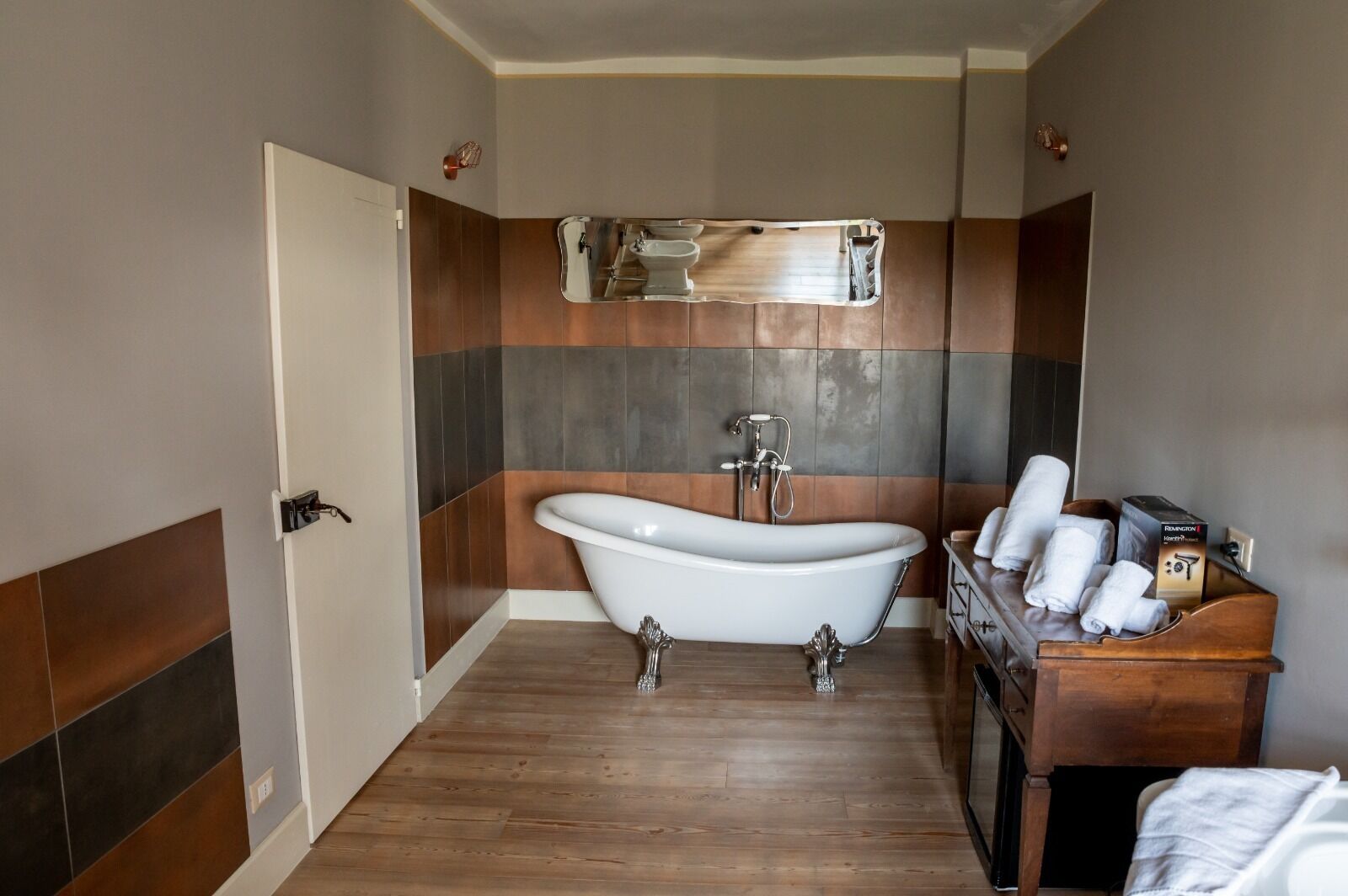 Un baño con bañera independiente, tocador de madera y un perchero para toallas.
