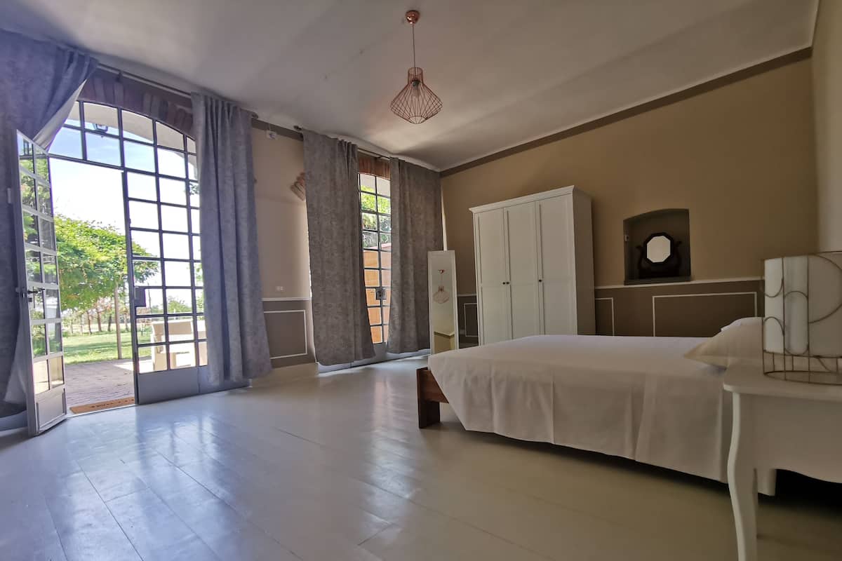 A spacious bedroom with a large bed, a wardrobe, and a desk.