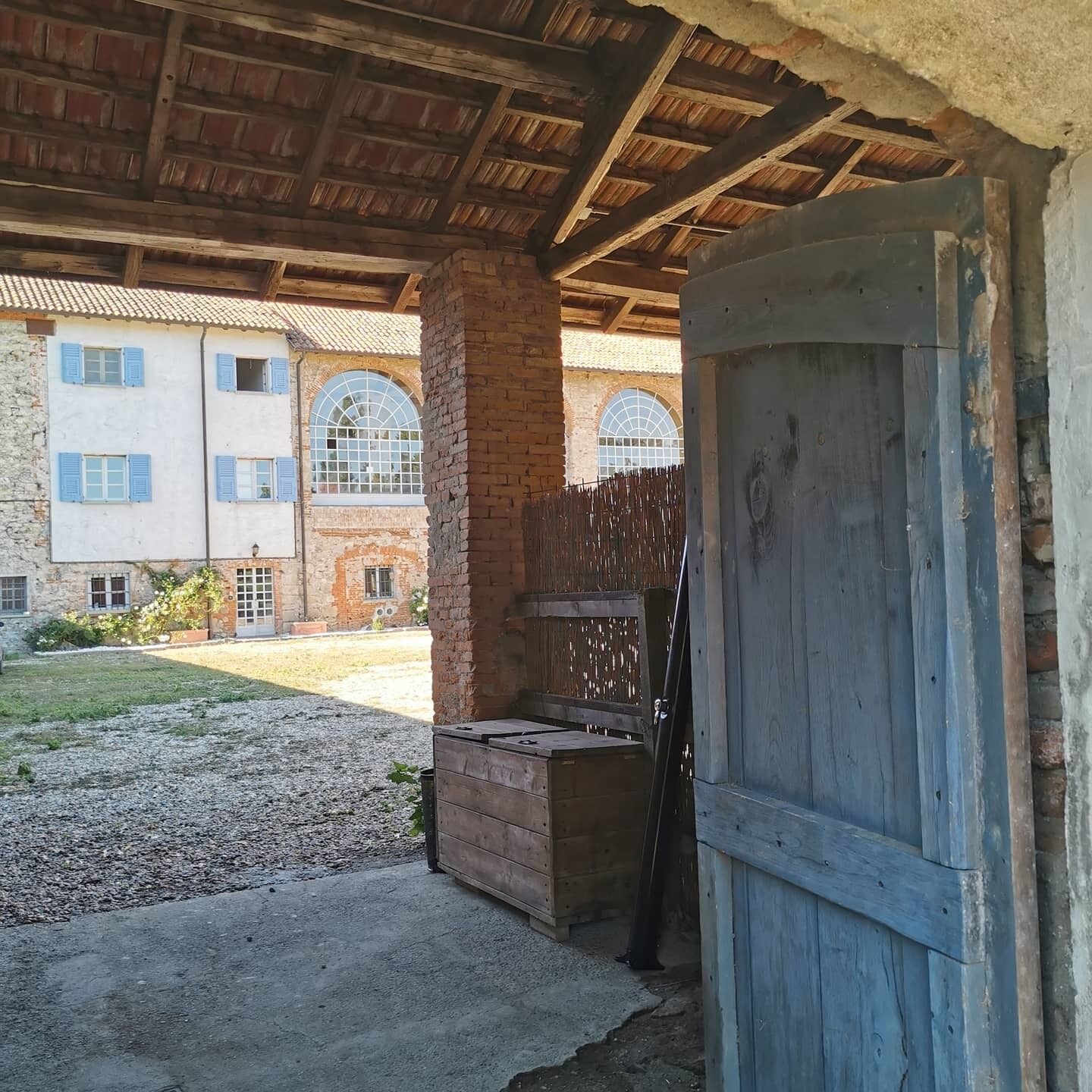A rustic building with a wooden door, a brick wall, and a metal gate.