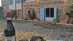 A rustic building with stone walls and arched windows, a bottle of wine, and a plate of food.