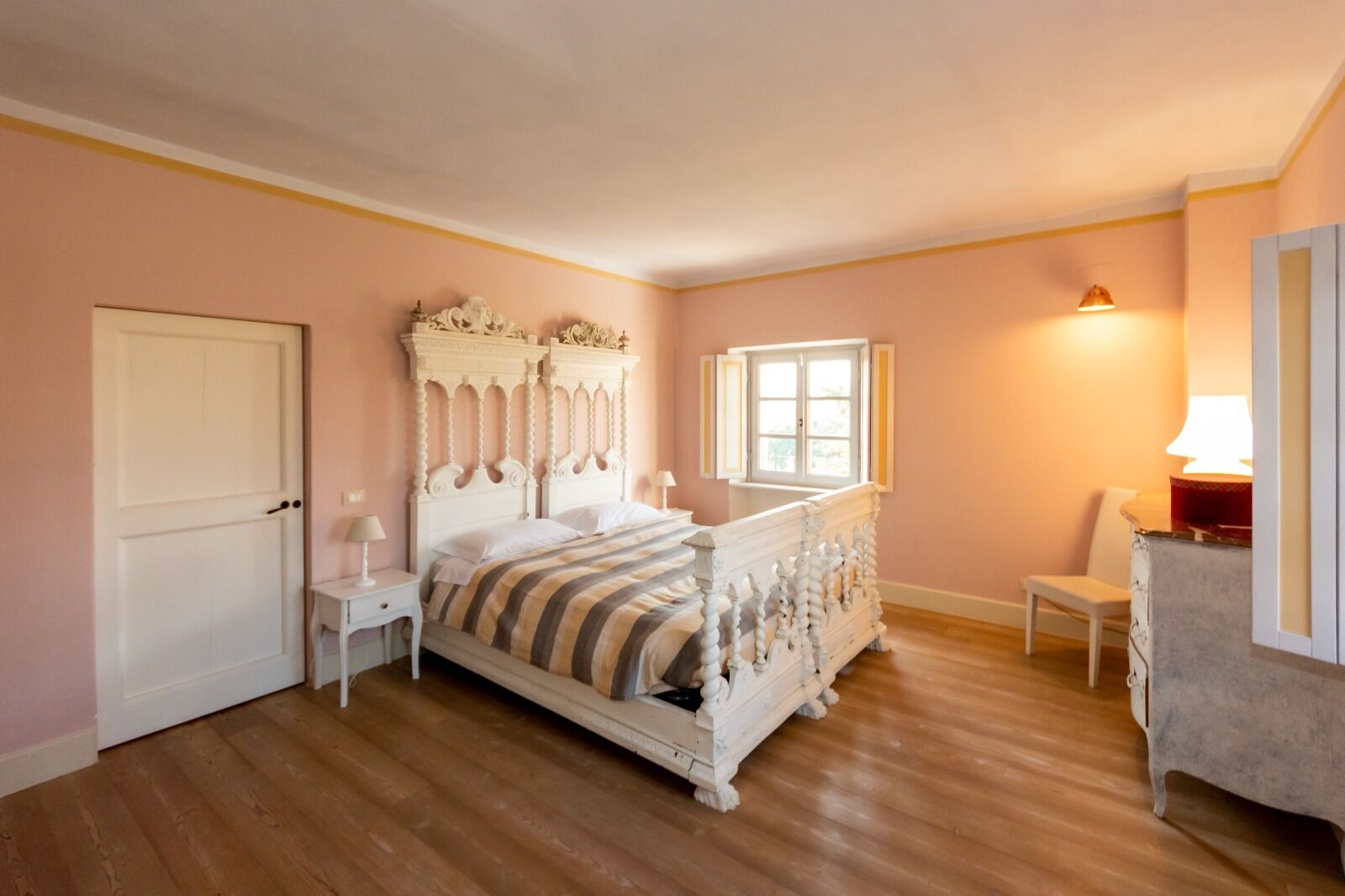 Ein Schlafzimmer mit einem großen Bett, einem Nachttisch, einem Sessel, einem Fenster und einer Tür.