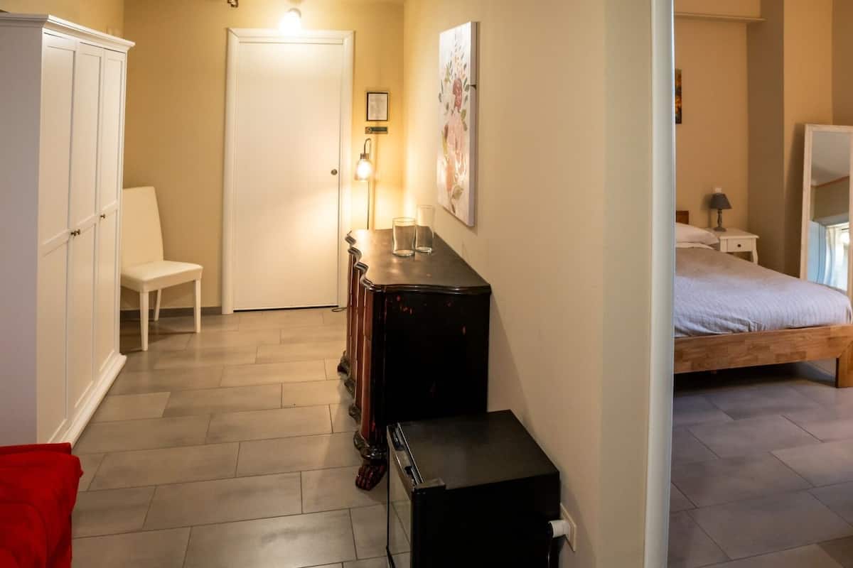 A bedroom with a bed, a desk, a chair, a wardrobe, and a lamp.