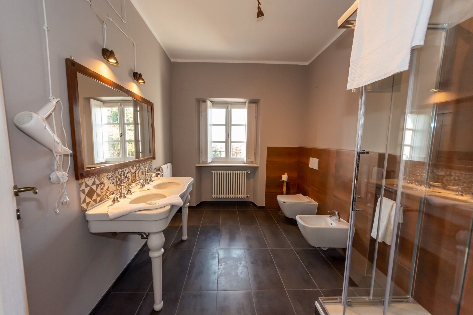 A modern bathroom with two sinks, a toilet, and a glass shower enclosure.