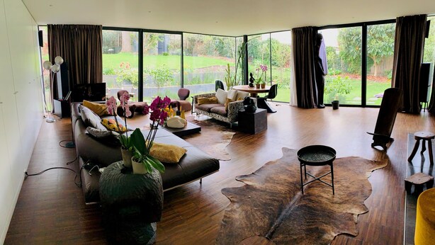 A spacious living room with a large window, a leather sofa, a coffee table, and a rug.