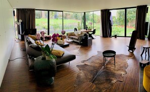 A spacious living room with a large window, a leather sofa, a coffee table, and a rug. - Maison D'architecte/ Paris et 2024 (Sèvres)