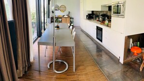 A modern kitchen with a large island, stainless steel appliances, and a dining area with a long table and chairs.