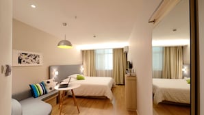 A hotel room with a bed, a desk with a laptop, a sofa, and a mirror. - Anmut (Dar es Salaam)