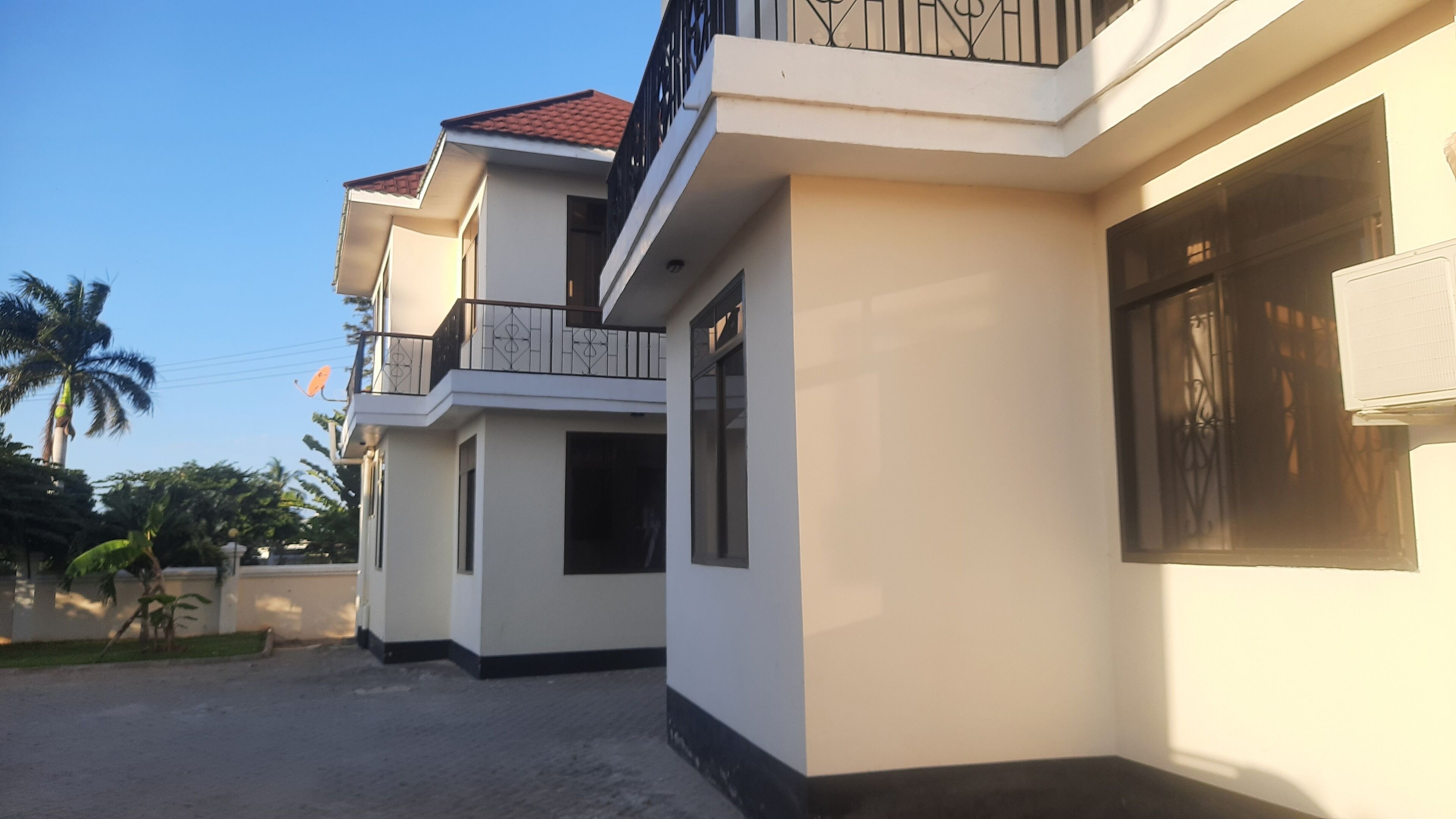 A modern two-story house with a balcony, a garage, and a driveway.