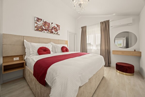 A modern bedroom with a large bed, a bedside table, a mirror, and a wall-mounted air conditioner. - Serenity Home Villa Tea with heated pool and pyrolysis salt water (Marčana)