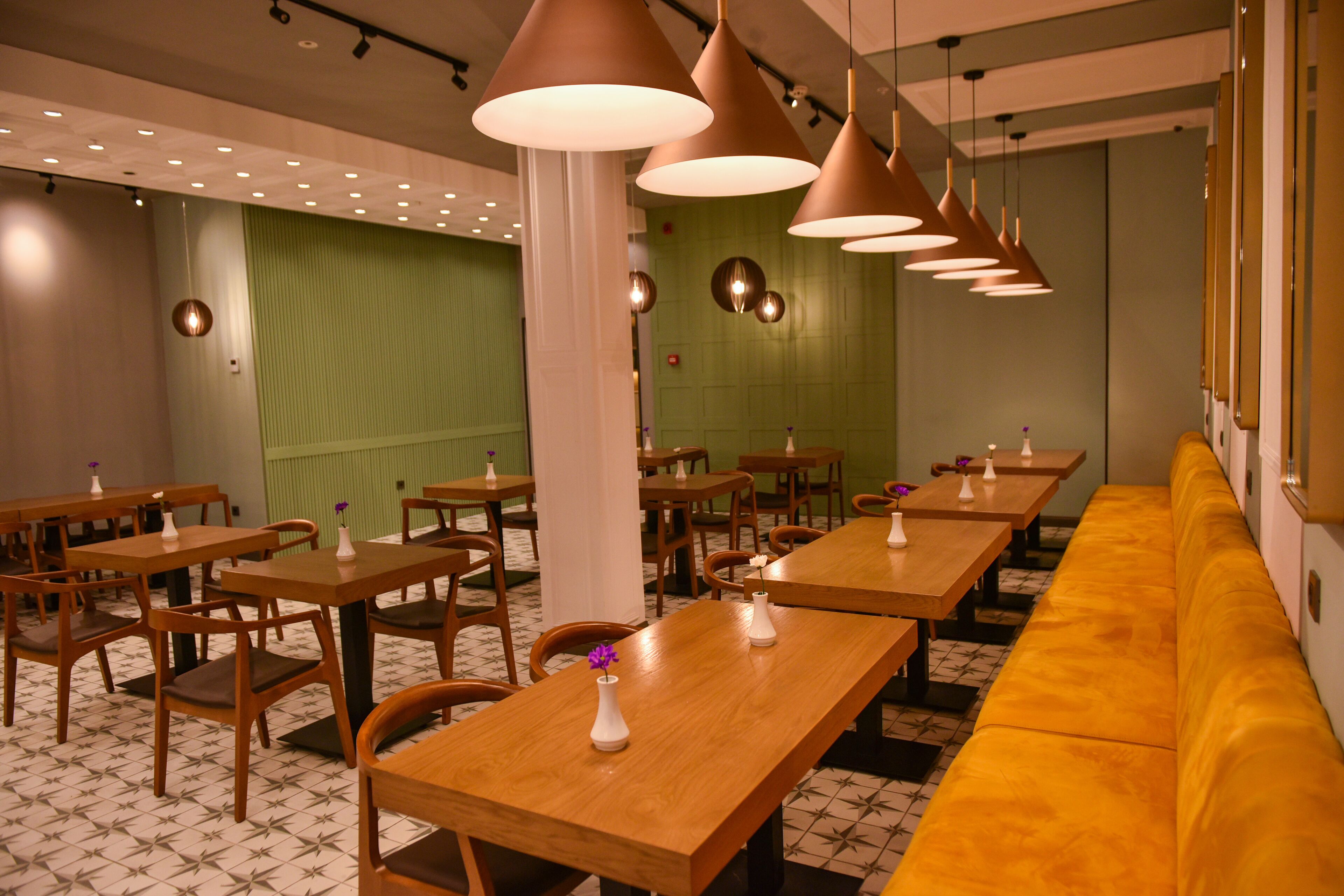 A restaurant interior with wooden tables, chairs, and a yellow bench.