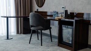 Una habitació d'hotel moderna amb un escriptori de fusta fosca, una cadira còmoda, un mirall gran i una televisió.