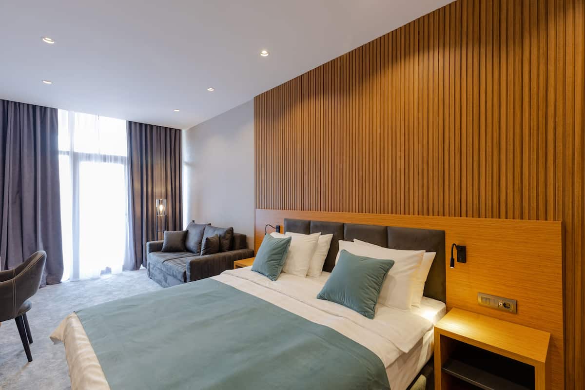 Una habitación de hotel moderna con una cama grande, un sofá, una silla y una pared decorativa de madera.