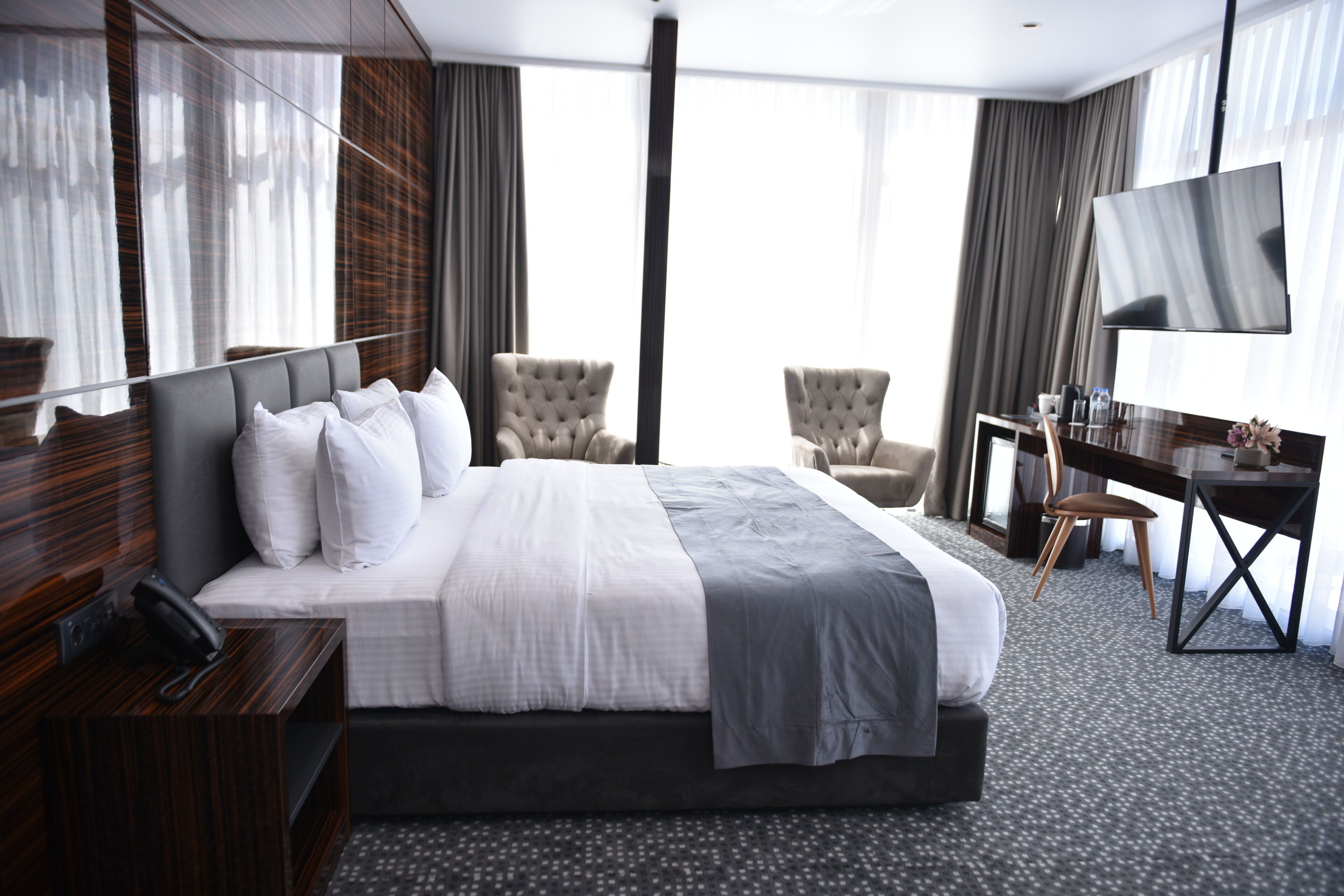 Una habitación de hotel con una cama grande, un escritorio, una silla, un televisor y un teléfono.