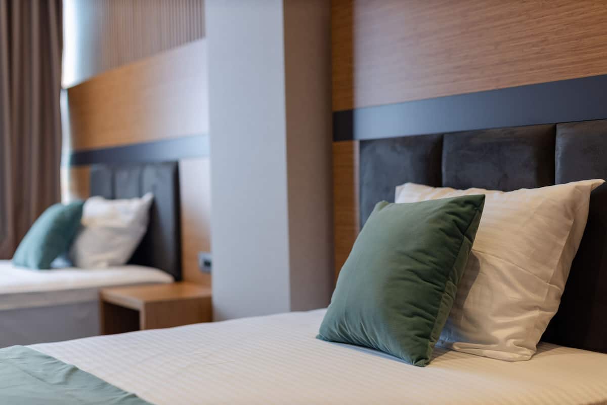 Una habitación de hotel con una cama grande, un cabecero y una mesita de noche.