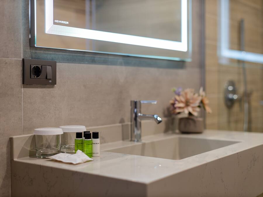 A bathroom with a large mirror, a sink, and a shower area.