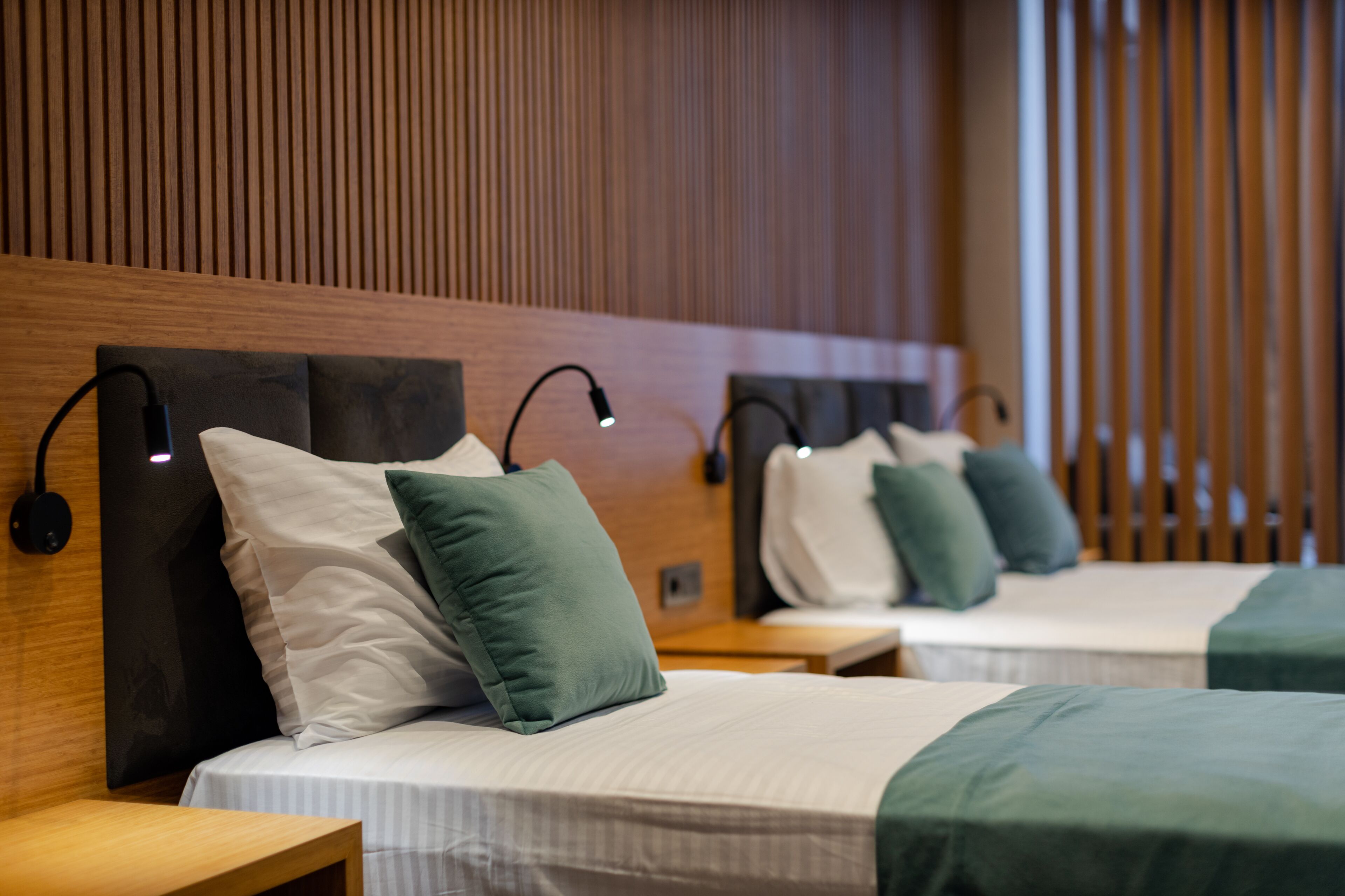 A hotel room with three beds, each with a headboard and bedside lamps.
