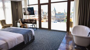 Habitació d'hotel amb un llit gran, un escriptori amb cadira, una televisió i una banyera.