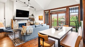 A modern living room with a fireplace, a large TV, and a dining area with a table and chairs. - Luxury Resort Penthouse at Peak 9 Base/on Main St. (Breckenridge)