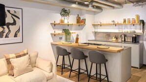 Eine moderne Küche mit Kochinsel, Barhocker und einer Essecke mit einer Couch.