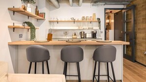 Eine moderne Küche mit Holzarbeitsplatten, Barhocker und hängenden Regalen mit Küchenutensilien.
