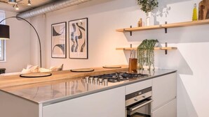Eine moderne Küche mit einer zentralen Kochinsel, Edelstahlgeräten und schlichtem Design.