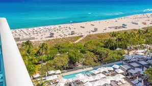 A beach resort with a pool area, beach umbrellas, and a view of the ocean.
